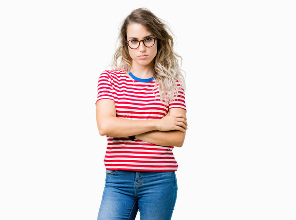Beautiful young blonde woman wearing glasses over isolated background skeptic and nervous, disapproving expression on face with crossed arms. Negative person. - Фото, изображение