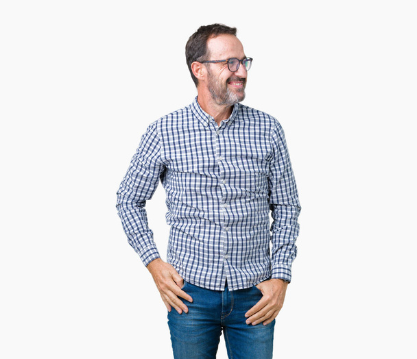 Handsome middle age elegant senior business man wearing glasses over isolated background looking away to side with smile on face, natural expression. Laughing confident. - Фото, изображение