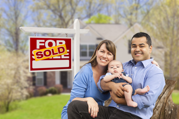Молодая семья перед продаваемой недвижимости знак и дом
 - Фото, изображение