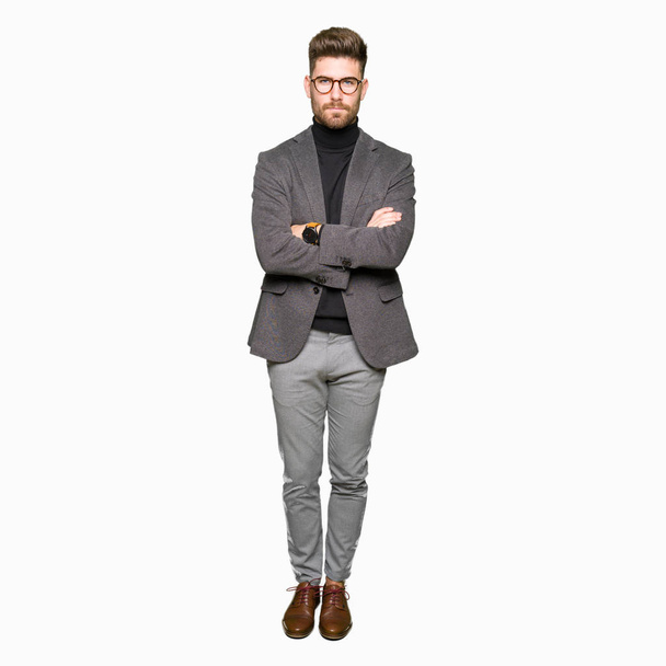 Young handsome business man wearing glasses skeptic and nervous, disapproving expression on face with crossed arms. Negative person. - Foto, Imagen