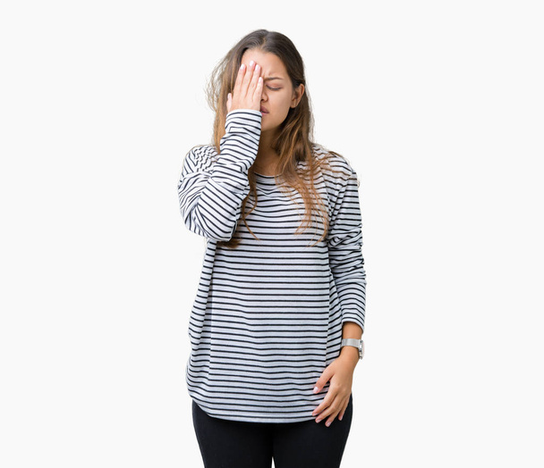 Mladá krásná bruneta žena na sobě pruhy svetr přes samostatný pozadí Yawning unavený, pokrývá polovinu obličeje, oči a ústa rukou. Tvář bolí bolí. - Fotografie, Obrázek