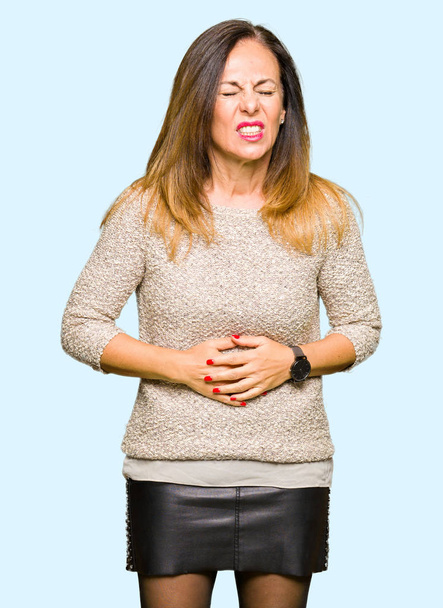 Mooie middelbare leeftijd vrouw dragen van mode trui met de hand op de maag omdat indigestie, pijnlijke ziekte onwel. Ache concept. - Foto, afbeelding
