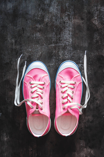 purple-pink-lilac sneakers with untied laces on a dark concrete  - Fotografie, Obrázek