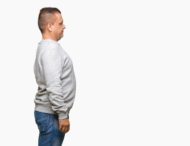 Middle age arab man wearing sport sweatshirt over isolated background looking to side, relax profile pose with natural face with confident smile. - Valokuva, kuva
