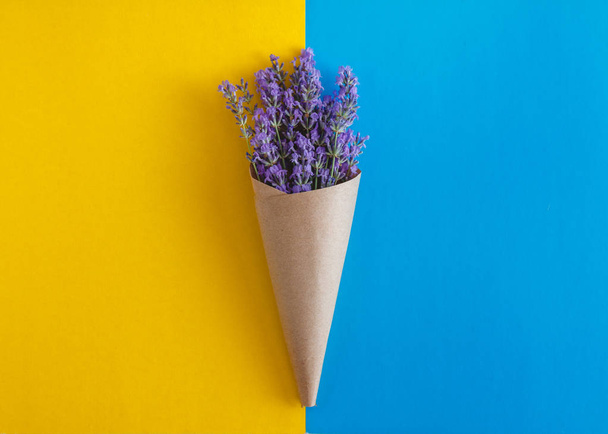 lavendel bloemen boeket in perkamentpapier kegel op een geel en - Foto, afbeelding