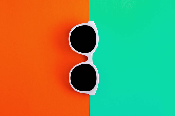 Sunny stylish white sunglasses on a bright blue-cyan and red-ora - 写真・画像