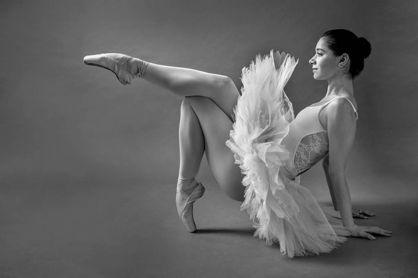eine junge Ballerina posiert auf dem Boden des Studios - Foto, Bild