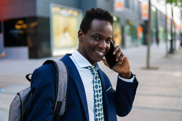 青いスーツを着て携帯電話を持つアフリカ系アメリカ人のビジネスマン - 写真・画像