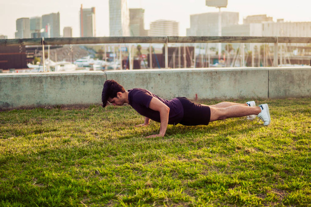 Young athletic man doing pushups exercises at park - Photo, Image