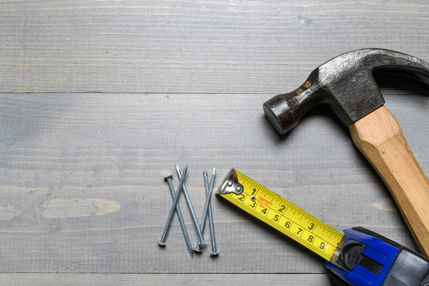 Hammer, nails and a yellow tape measure on wood - Foto, imagen