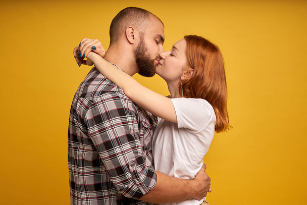 Профиль фото молодых красивых влюбленных людей, выражающих любовь и привязанность, целующих друг друга с закрытыми глазами, изолированными на желтом фоне
 - Фото, изображение