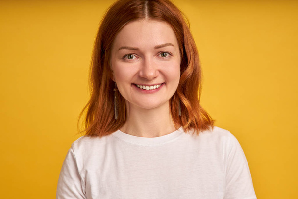 Valokuva lähikuva optimistinen nainen 20s kihara inkivääri hiukset hymyillen kameran eristetty keltaisella taustalla
 - Valokuva, kuva