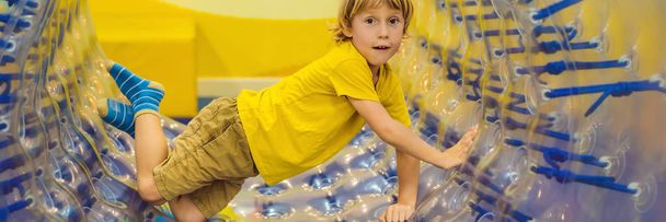 Cute little boy, playing in Zorb a rolling plastic cylinder ring with a hole in the middle, intdoor BANNER, LONG FORMAT - Foto, afbeelding