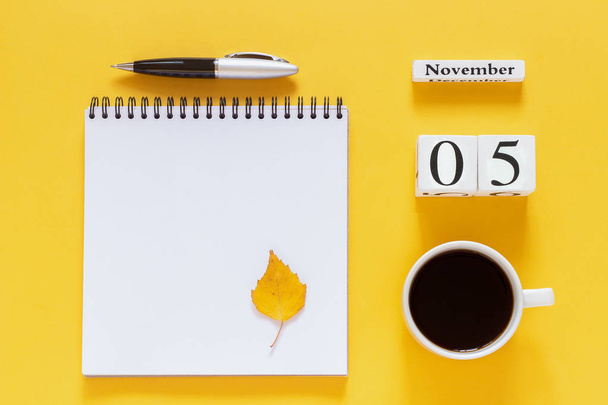 calendar November 5 cup of coffee, notepad with pen and yellow leaf on yellow background - Фото, изображение