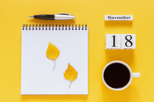 calendar November 18 cup of coffee, notepad with pen and yellow leaf on yellow background - Фото, изображение