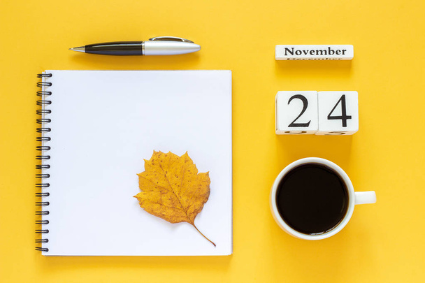 calendar November 24 cup of coffee, notepad with pen and yellow leaf on yellow background - Фото, зображення