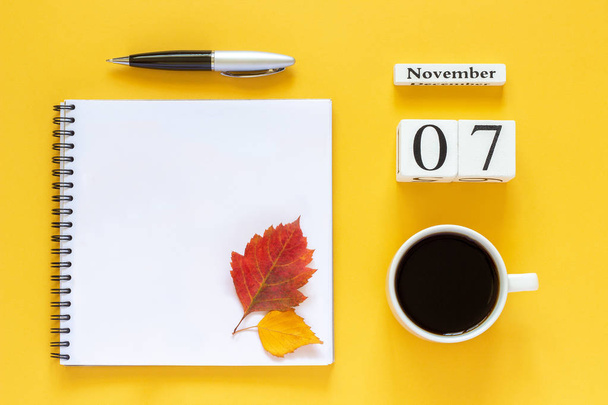 calendar November 07 cup of coffee, notepad with pen and yellow leaf on yellow background - Fotografie, Obrázek