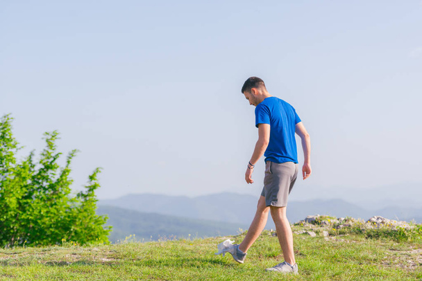 Een fit mannelijke atleet bereidt zich voor op een work out in de natuur terwijl l - Foto, afbeelding