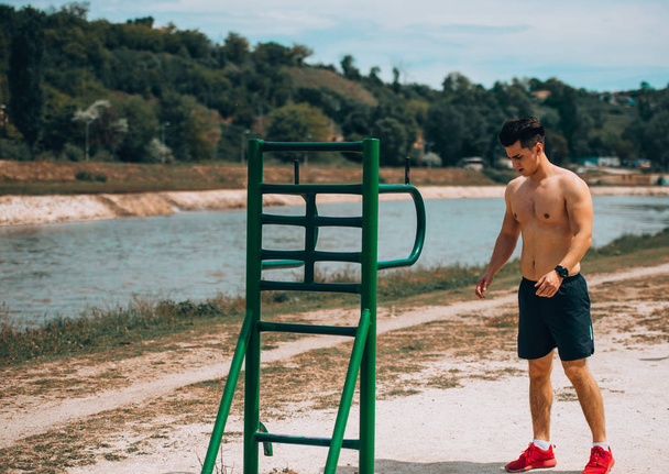 Fitness gömleksiz adam açık havada vücut kasları germe - Fotoğraf, Görsel