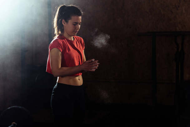 Modelo de fitness femenino aplaudiendo manos con talco en polvo
 - Foto, Imagen