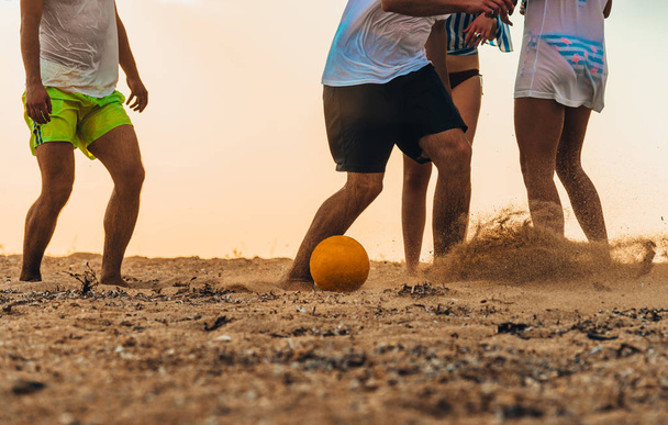 Grupo de amigos multiétnicos jogando futebol na praia
 - Foto, Imagem