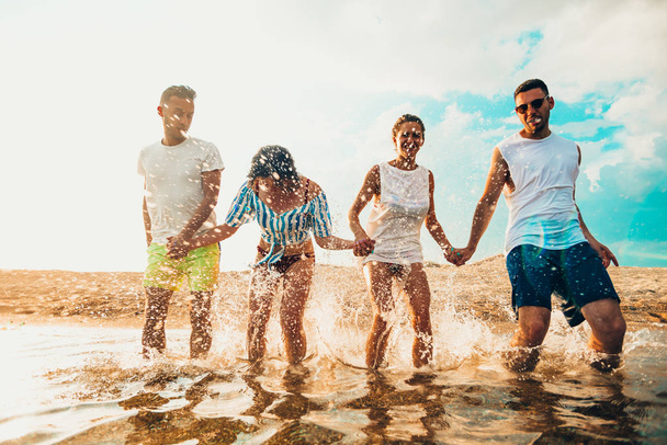 Felizes amigos sorridentes pulando na praia
 - Foto, Imagem