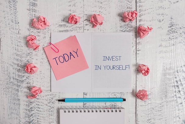 Text sign showing Invest In Yourself. Conceptual photo nvesting in a coach or a training to learn new things Squared spiral notepad clip note highlighter paper balls wooden background. - Photo, Image