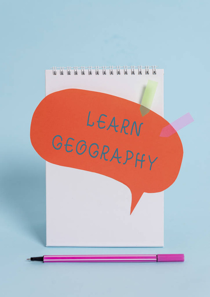 Conceptual hand writing showing Learn Geography. Business photo text study of physical features of earth and its atmosphere Spiral notepad speech bubble arrow pen lying pastel background. - Photo, Image