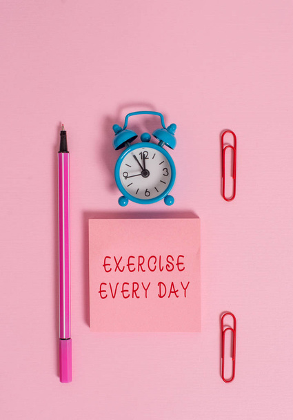 Conceptual hand writing showing Exercise Every Day. Business photo text move body energetically in order to get fit and healthy Metal alarm clock blank notepad marker clips colored background. - Photo, Image