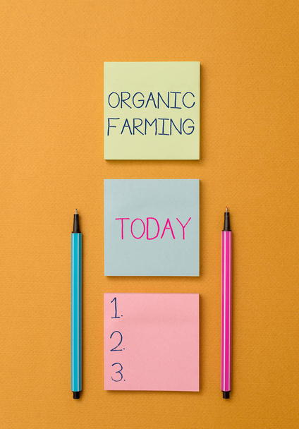 Writing note showing Organic Farming. Business photo showcasing an integrated farming system that strives for sustainability Front view colored sticky note two ballpoints cool yolk background. - Photo, Image
