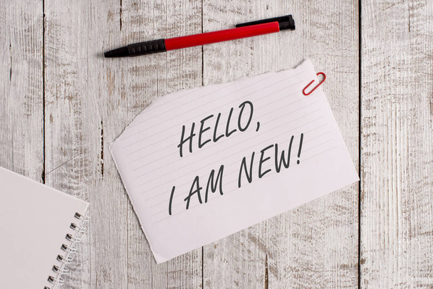 Текст для написания слов Hello I Am New. Бизнес-концепция представления себя в группе в виде свежей рабочей или студенческой порванной бумаги и листа ноутбука с ручкой на деревянном столе
. - Фото, изображение