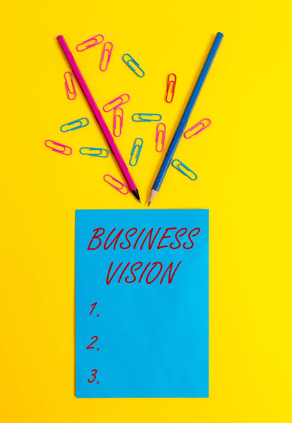 Texto de escrita de palavras Business Vision. Conceito de negócio para crescer o seu negócio no futuro com base em seus objetivos em branco papel folha mensagem lembrete lápis clipes fundo colorido
. - Foto, Imagem