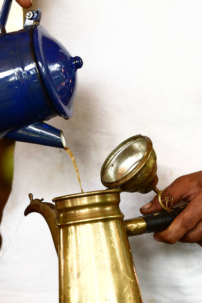 Рука наливає свіжозварену каву з старовинного кавового горщика
 - Фото, зображення