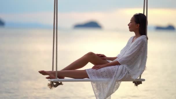 кадри красивої азіатки, що сидить на гойдалці на березі моря під час літніх канікул
 - Кадри, відео