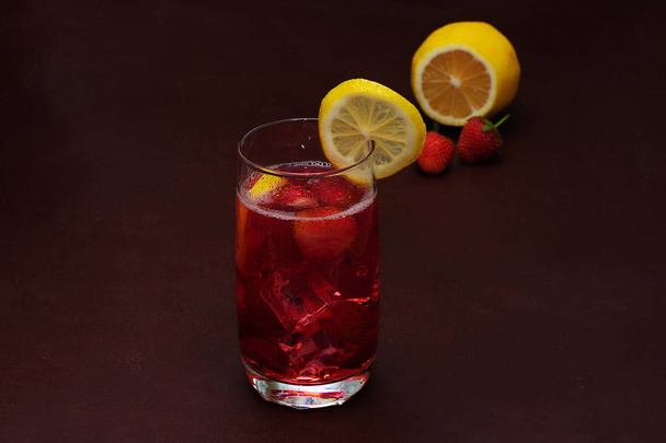 Drink with ice from strawberries on a dark background. Fresh strawberry cocktail. Fresh summer cocktail with strawberry and ice cubes. Glass of strawberry soda drink on dark background. - Photo, Image