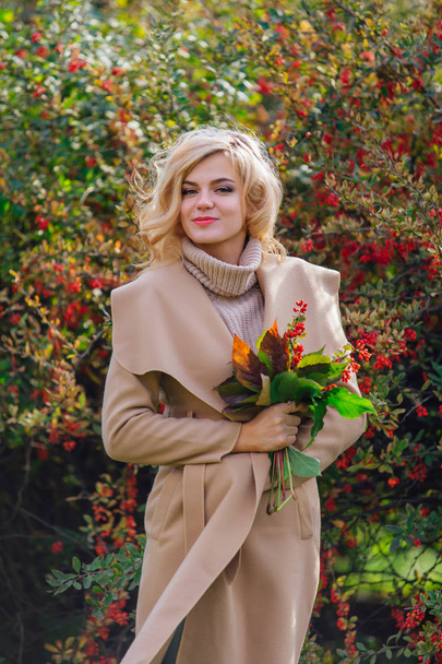 Beautiful elegant woman standing next barberry bush in autumn park - Zdjęcie, obraz