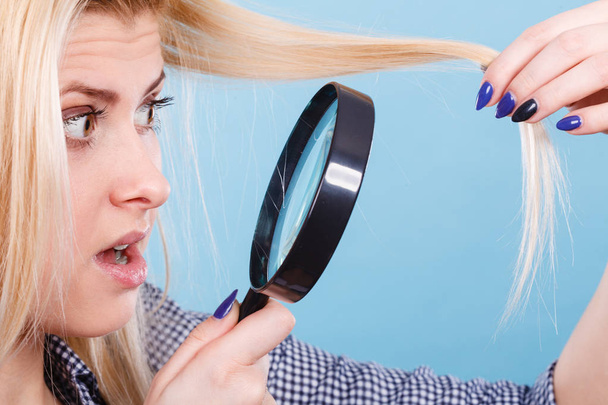 Woman looking at hair through magnifying glass - Фото, изображение