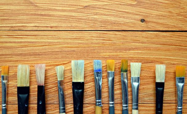 Pinceles usados frente a un fondo de madera - diferentes tipos y formas de pinceles con diferentes colores
 - Foto, Imagen