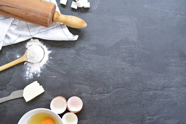 Bach gebruiksvoorwerpen op een keuken bord-eieren, meel, boter en suiker-concept met plaats voor tekst  - Foto, afbeelding