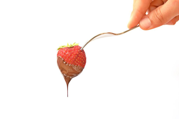 Fresh strawberries, stuck on the tip of a fork, dip in liquid chocolate - close up and isolated - Fotoğraf, Görsel