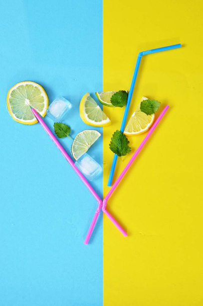 Concepto para bebida de verano - Las pajitas componen el vaso de los limones, limas, menta y hielo flotando sobre un fondo colorido - Ilustración abstracta de un refresco veraniego con espacio para el texto
  - Foto, imagen