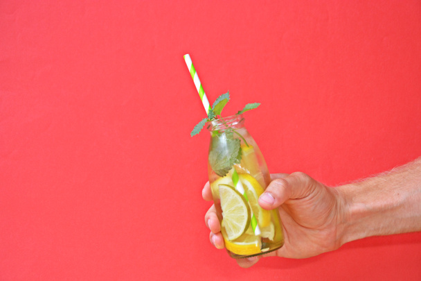 Держа в руке стакан льда, лаймов, лимонов и мяты - идеальное сочетание для души на красочном фоне с пространством для текста или других элементов
  - Фото, изображение