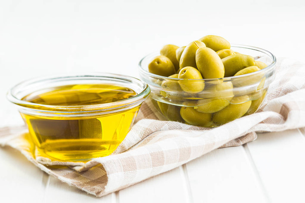 Green olives and olive oil in glass bowl. - Foto, afbeelding