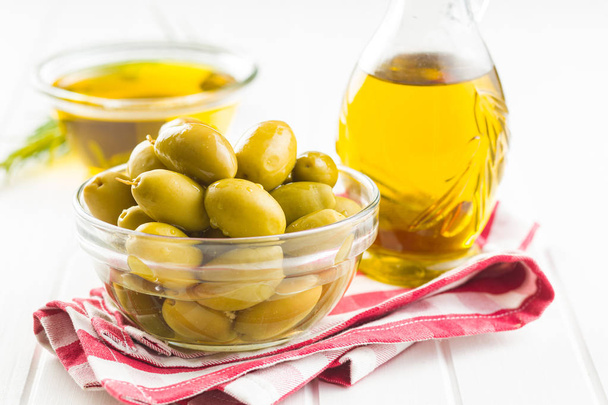 Green olives and olive oil in glass bowl. - Foto, Imagen