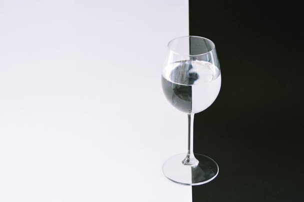 A água contida em um copo de vinho quebra o fundo preto e branco exatamente na direção oposta arte de esclarecer a reflexão da luz através de corpos redondos conceito em preto e branco
 - Foto, Imagem
