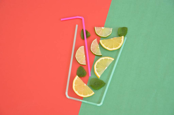 Kreatives Layout Erdbeer-Limonade Zutaten - Zitrone, Zitrusfrüchte, Eis fallen in Glas mit Cocktail-Strohhalmen auf buntem Hintergrund gemacht. Sommergetränke. Minimal Food Konzept. Selektiver Fokus. - Foto, Bild