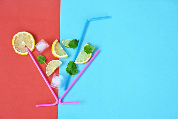 Concept voor de zomer drankje-rietjes make-up het glas in de citroenen, Limes, Mint en ijs drijft tegen een kleurrijke achtergrond-abstracte illustratie van een zomerse refreshmentmet ruimte voor tekst  - Foto, afbeelding