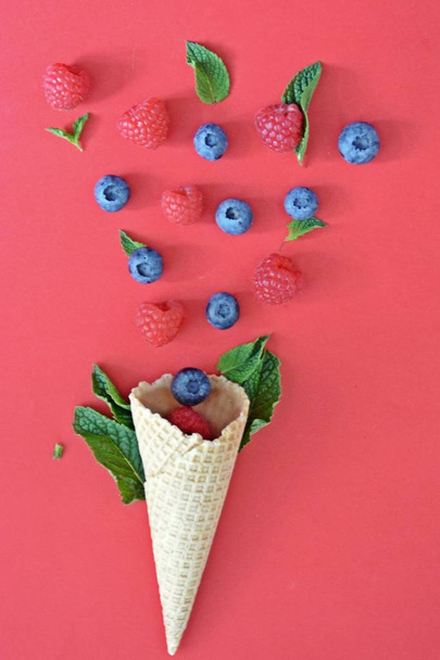 Un cône de crème glacée aux myrtilles, framboises et menthe sur un fond coloré comme symbole d'une crème glacée fruitée estivale rafraîchissante
 - Photo, image