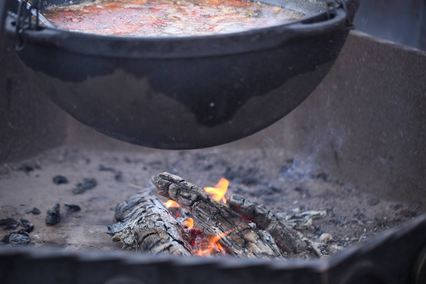 Cocinar afuera en el fuego en un caldero grande
. - Foto, imagen