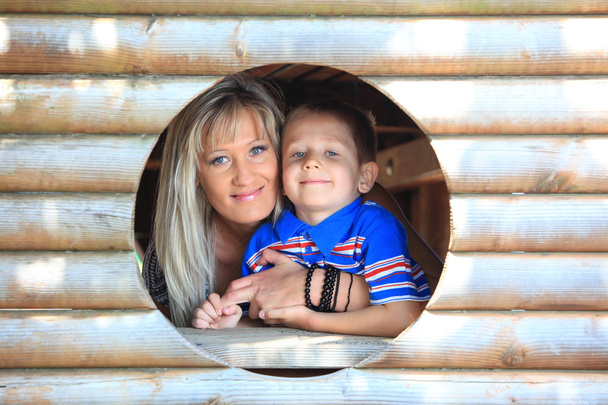 Mother and son peeks through hole at playground - Φωτογραφία, εικόνα